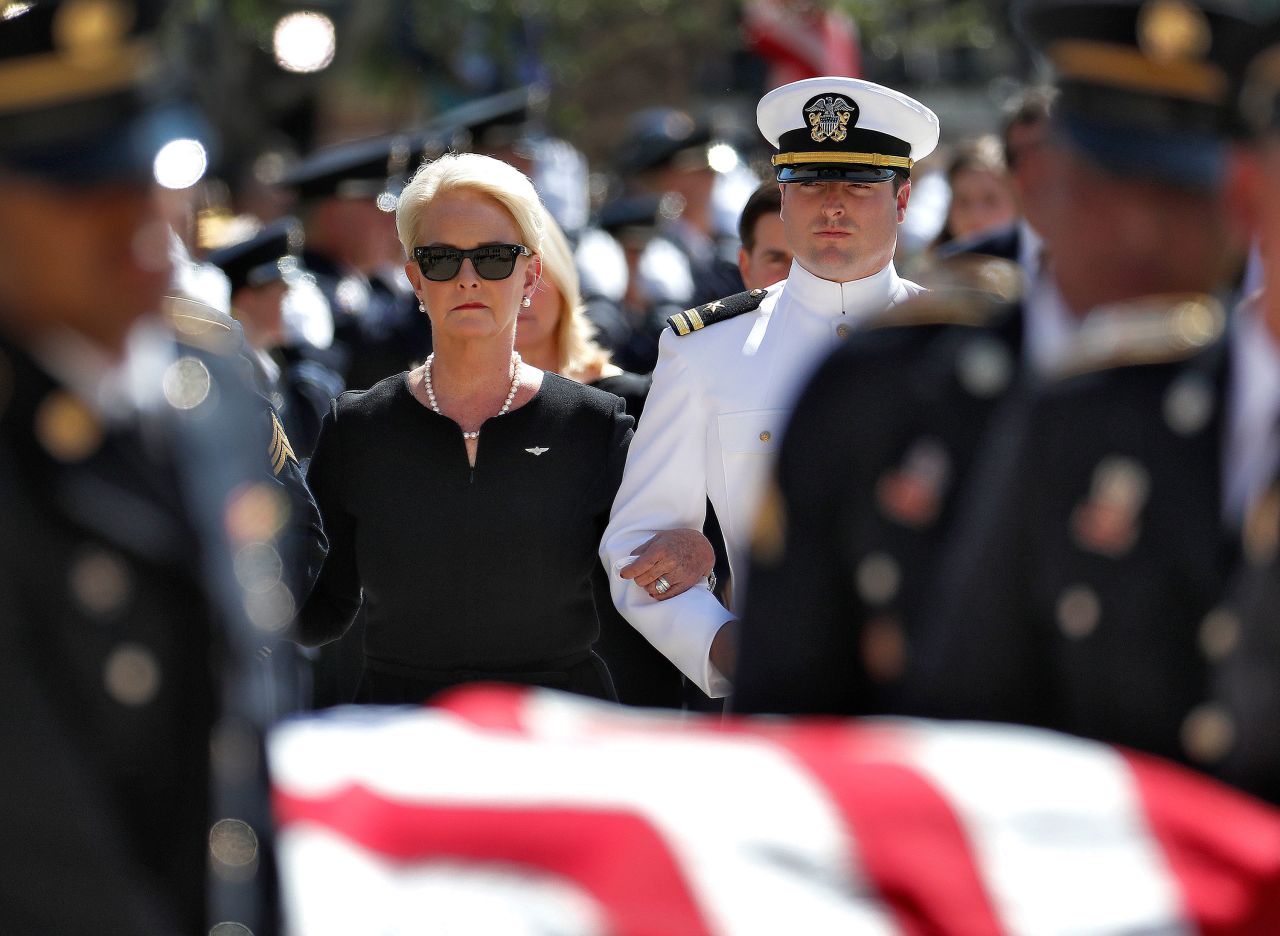 Cindy McCain and her son Jack follow military personnel carrying the casket.