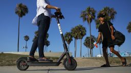 LOS ANGELES, CA - AUGUST 13:  A woman rides a Bird shared dockless electric scooter along Venice Beach on August 13, 2018 in Los Angeles, California. Shared e-scooter startups Bird and Lime have rapidly expanded in the city. Some city residents complain the controversial e-scooters are dangerous for pedestrians and sometimes clog sidewalks. A Los Angeles Councilmember has proposed a ban on the scooters until regulations can be worked out.  (Photo by Mario Tama/Getty Images)