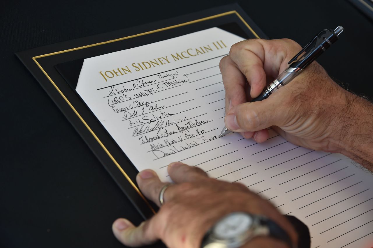 A man signs a register before paying tribute to McCain on Wednesday.