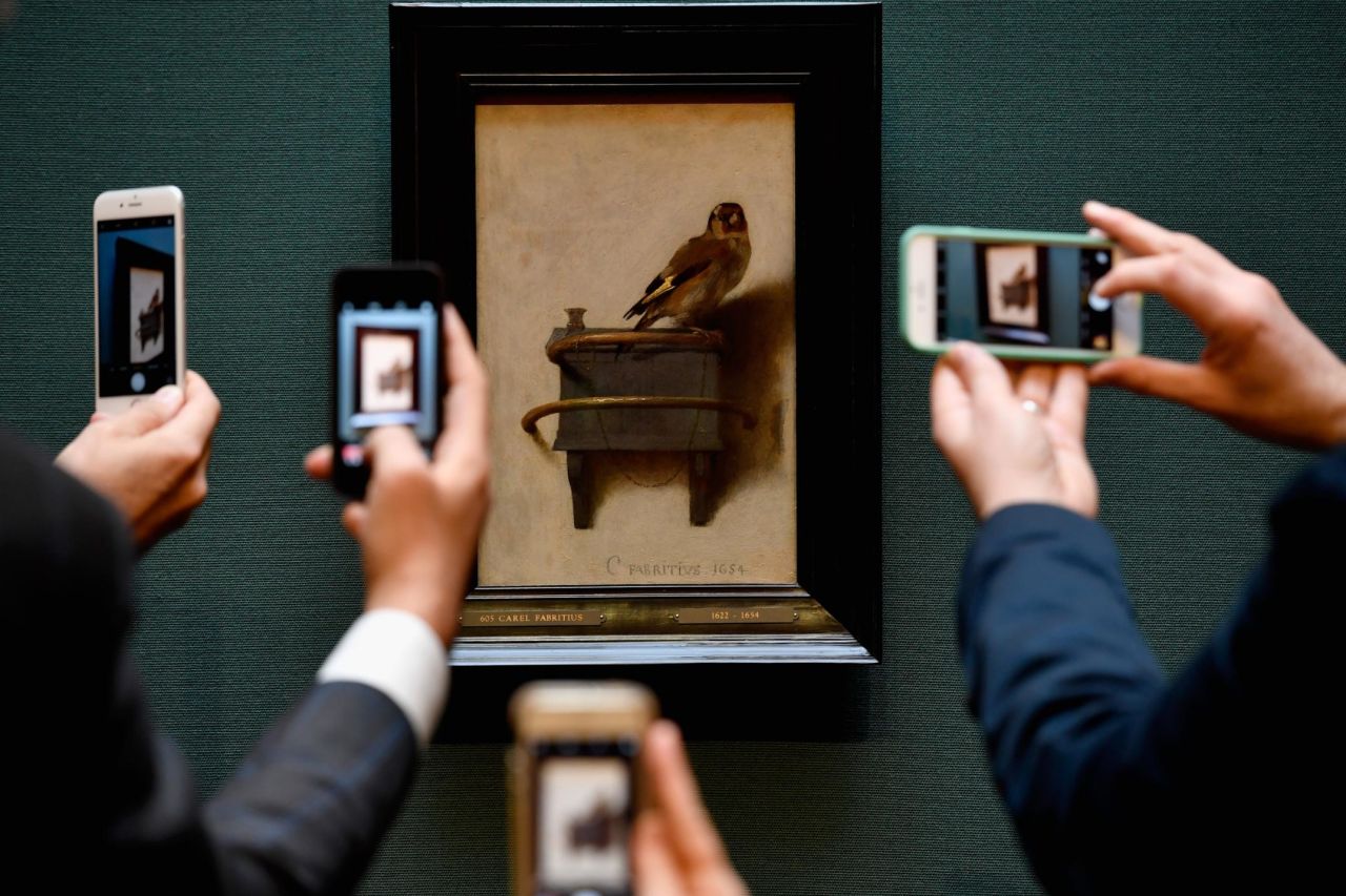 Gallery staff take photos on their phones of the painting by Carel Fabritius 'The Goldfinch' at the Scottish National Gallery on November 3, 2016. 