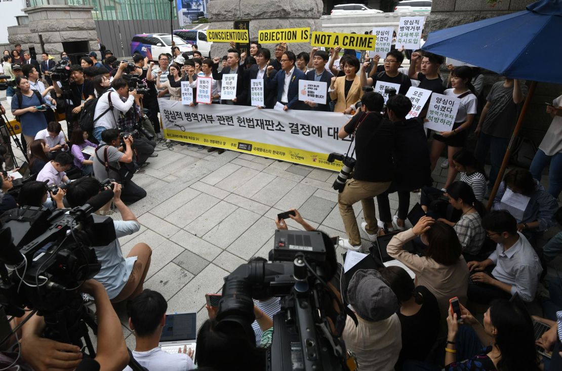 South Korean activists and conscientious objectors to military service hold yellow banners reading "Conscientious objection is not a crime" during a rally outside the Constitutional Court in Seoul on June 28, 2018.