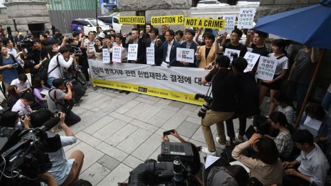 South Korean activists and conscientious objectors to military service hold yellow banners reading "Conscientious objection is not a crime" during a rally outside the Constitutional Court in Seoul on June 28, 2018.