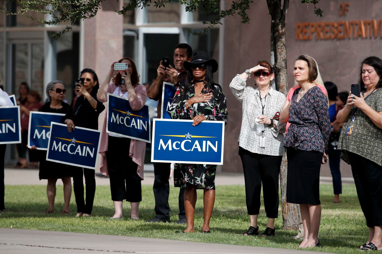 People in Phoenix watch a motorcade carrying McCain's casket on Thursday.
