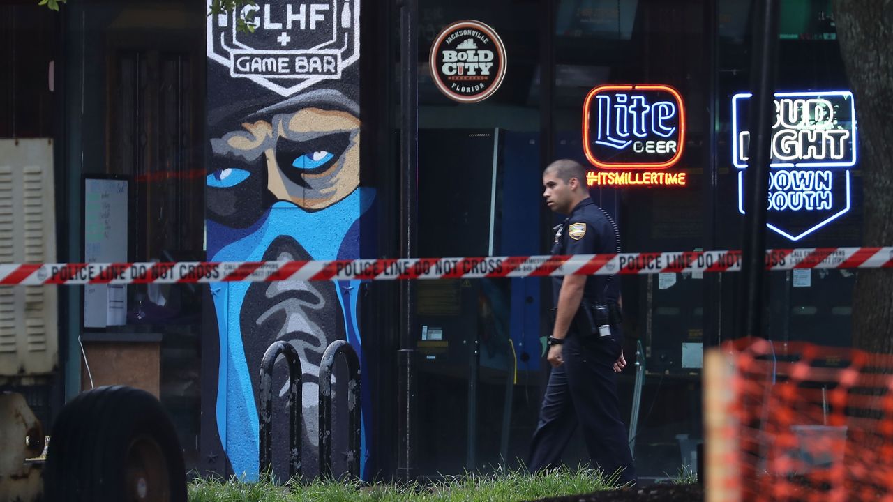 A law-enforcement officer walks past the GLHF Game Bar, where <a href="https://www.cnn.com/2018/08/27/us/jacksonville-madden-tournament-shooting/index.html" target="_blank">a mass shooting</a> occurred Sunday, August 26, in Jacksonville, Florida. Police said David Katz, 24, killed two people and wounded 10 others before taking his own life at a video-game tournament.