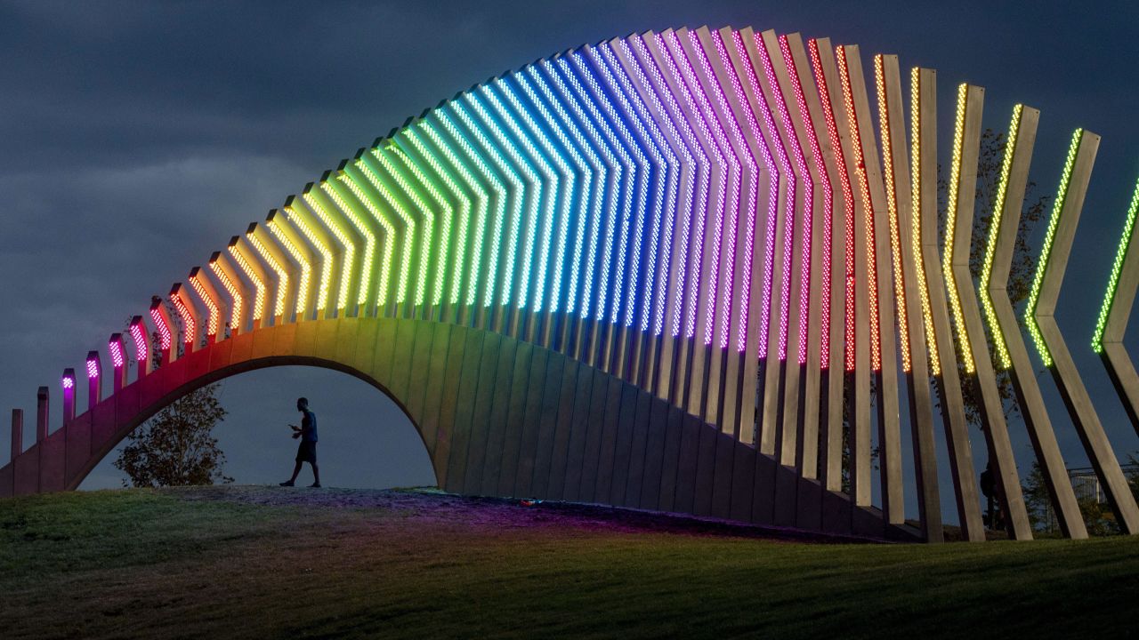 A man walks under Moving Surfaces, a giant steel and light sculpture in Ottawa's Lansdowne Park, on Saturday, August 25. It was rainbow-colored for Pride Week.