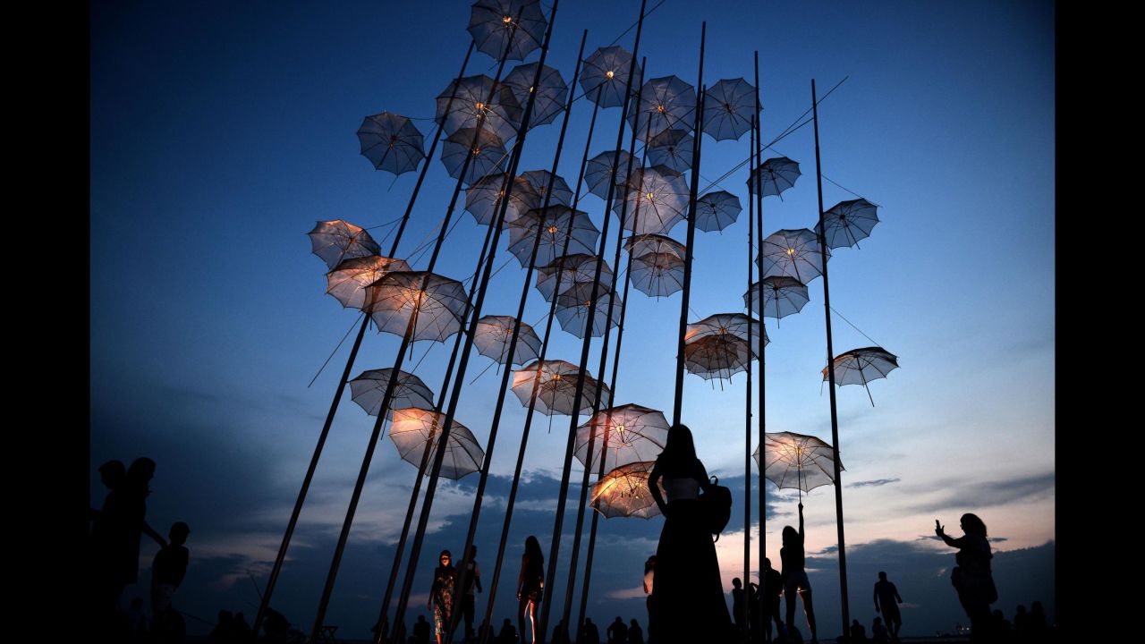 People in Thessaloniki, Greece, take photos under "Umbrellas," a sculpture by George Zongolopoulos, on Sunday, August 26.