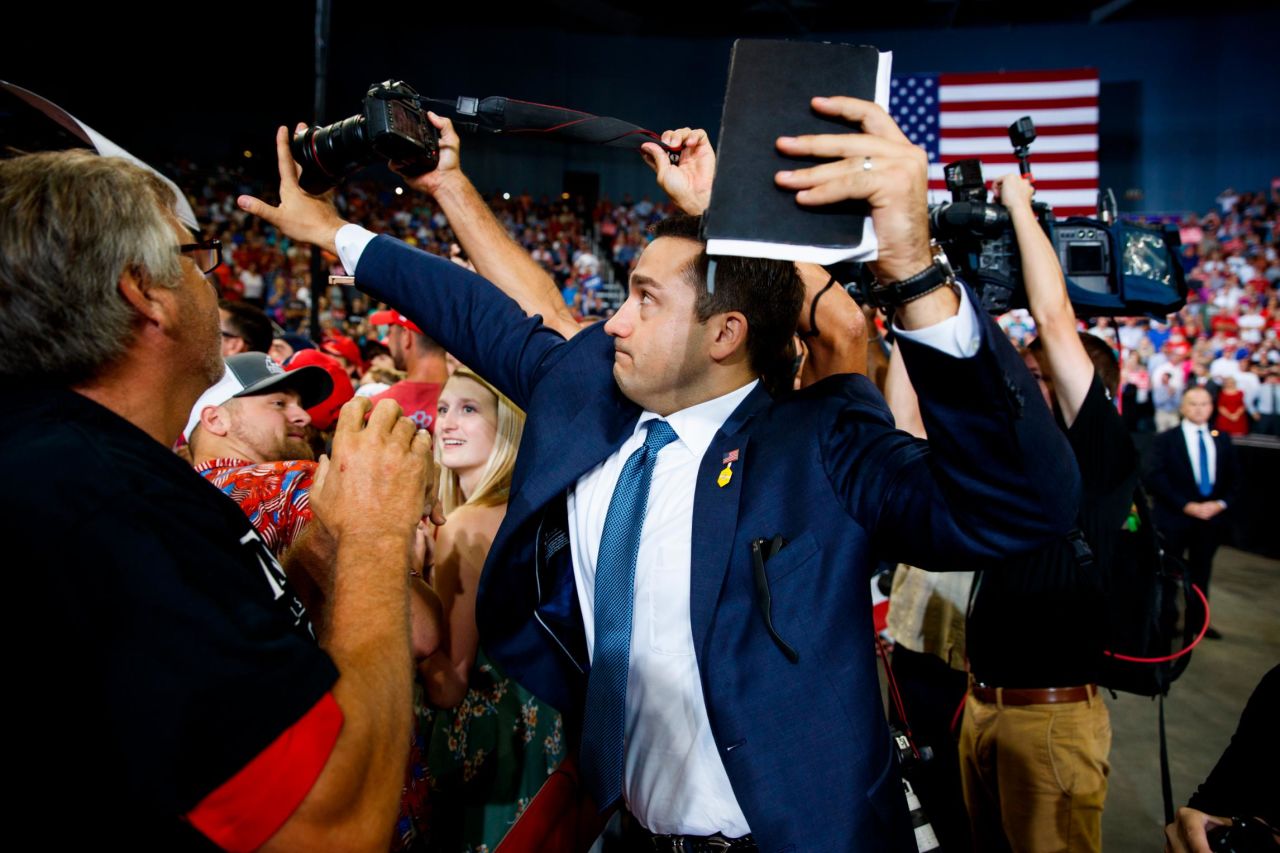 A staff member for US President Donald Trump blocks a camera as a photojournalist attempts to take a photo of a protester during a campaign rally in Evansville, Indiana, on Thursday, August 30.