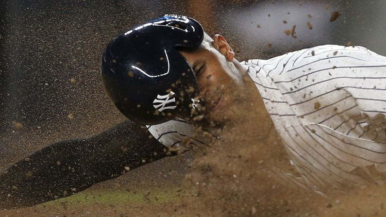 New York Yankees' Aaron Hicks dives into home plate to score on a single by Miguel Andújar against the Detroit Tigers on Thursday, August 30.