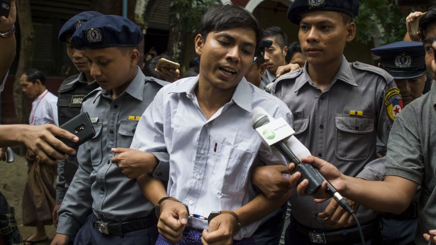 Detained Myanmar journalist Kyaw Soe Oo (C) speaks to reporters under escort by police during a break in his ongoing trial at a court in Yangon on July 2, 2018 for the final arguments on pre-trial hearings. - Two Reuters journalists appeared at a Myanmar court on July 2, while over six months in custody for allegedly breaching a secrecy law while investigating atrocities against Rohingya Muslims, as calls grow for the "spurious" case to be dropped. (Photo by YE AUNG THU / AFP)        (Photo credit should read YE AUNG THU/AFP/Getty Images)