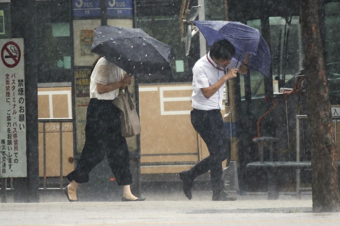 Pedestrians try to hold their umbrellas while struggling with strong winds in Yokohama, near Tokyo.