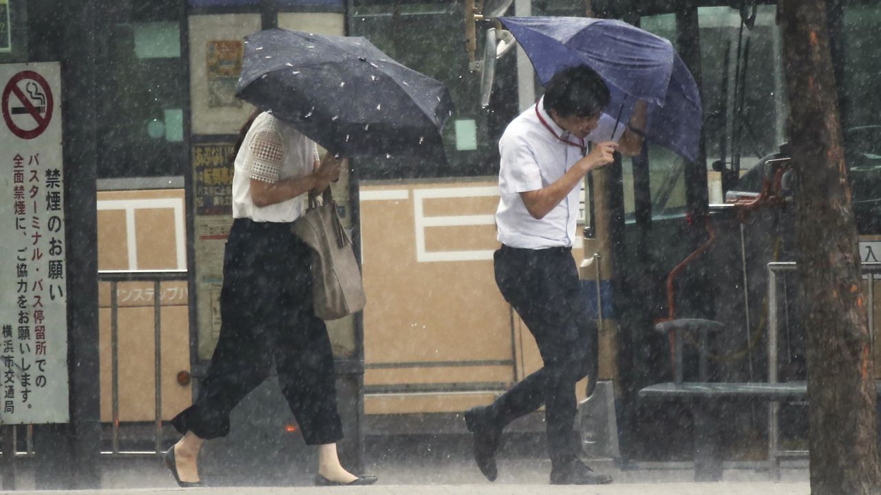 Pedestrians try to hold their umbrellas while struggling with strong winds in Yokohama, near Tokyo.