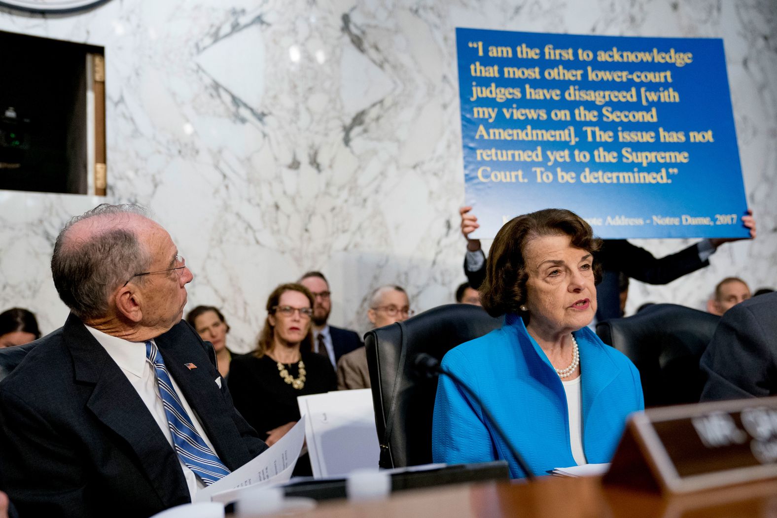 A poster on Wednesday shows a quote of Kavanaugh's from 2017. Sen. Dianne Feinstein, front right, <a href="index.php?page=&url=https%3A%2F%2Fwww.cnn.com%2Fpolitics%2Flive-news%2Fkavanaugh-hearing-dle%2Fh_71a89f195edbb405ce3fc4f2d93178ef" target="_blank">was questioning Kavanaugh's opinion on assault weapons,</a> specifically what he's said in the past about how "common use" dictates the rights of Americans to own and continue to use them. Kavanaugh said he follows Supreme Court precedents on the issue specifically as they relate to the Second Amendment, though he said that doesn't mean "that there is no gun regulation permissible."