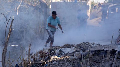 Syrians use dirt to put out a fire at the scene of a reported air strike in the district of Jisr al-Shughur, in the Idlib province, on September 4, 2018. 