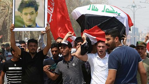 Mourners chant anti-government slogans Monday night while carrying the Iraqi flag-draped coffin of Mekki Yasser, seen in the poster, a protester whose family and activists said he was killed during a protest.