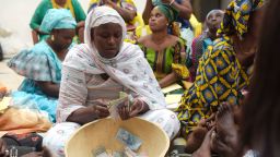 Binta Ndoye sits on a mat in a home in Grand-Mbao, on March 9, 2017, as she counts the money for a "cagnotte de la tontine" scheme, as members look on.The "cagnotte de la tontine", is a  jackpot  set-up by a cooperative scheme organised among locals in the Medina area of Grand-Mbao, a neighbourhood on the tip of Africa's west coast on the outskirts of the capital Dakar. A common practice throughout Africa, many Senegalese take part in centuries-old microcredit schemes called "tontines" to finance their projects. 