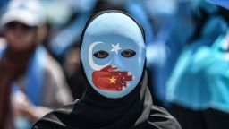 TOPSHOT - A demonstrator wearing a mask painted with the colours of the flag of East Turkestan and a hand bearing the colours of the Chinese flag attends a protest of supporters of the mostly Muslim Uighur minority and Turkish nationalists to denounce China's treatment of ethnic Uighur Muslims during a deadly riot in July 2009 in Urumqi, in front of the Chinese consulate in Istanbul, on July 5, 2018. - Nearly 200 people died during a series of violent riots that broke out on July 5, 2009 over several days in Urumqi, the capital city of the Xinjiang Uyghur Autonomous Region, in northwestern China, between Uyghurs and Han people. (Photo by OZAN KOSE / AFP)        (Photo credit should read OZAN KOSE/AFP/Getty Images)