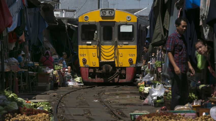 MAEKLONG, THAILAND - AUGUST 29: The train arrives  at the train market in Maeklong, Thailand on August 29, 2013.  The famous market train runs along the Maeklong Railway which is a railway that travels for nearly 67 kilometres between Wongwian Yai, outside of Bangkok to Samut Songkhram in Central Thailand. The market is located around the train track which means that whenever a train approaches, the shop fronts are moved back from the rails, then replaced moments after the train has passed. (Photo by Paula Bronstein/Getty Images)