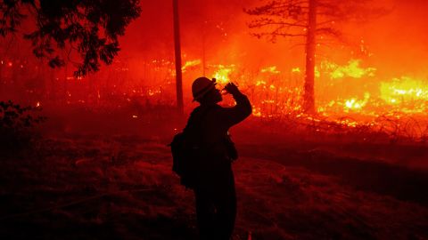 A firefighter drinks water as flames spread Thursday in Pollard Flat.