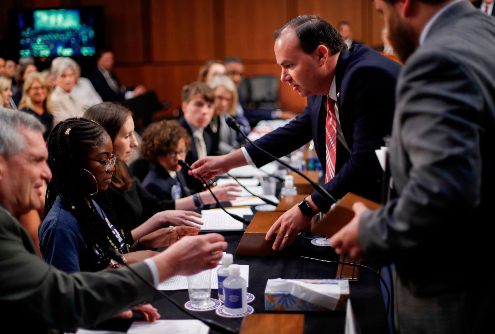 Sen. Mike Lee helps replace an audio microphone for witnesses who were testifying on Friday.