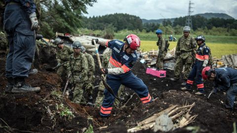 Soldiers and rescue workers search through mud covering a building in Atsuma, September 7, 2018