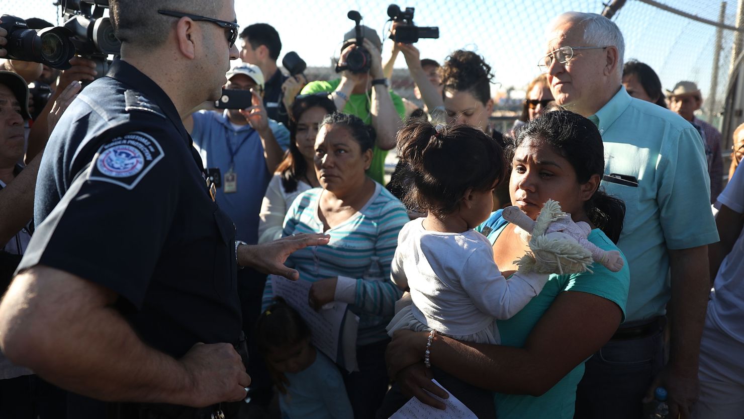 US Border Patrol agent Ray Provencia informs Angelica and Karla (who didn't want their last names used), along with Ruben Garcia, director of the Annunciation House, (R) who was helping them cross, that they will have to wait at the top of the Paso Del Norte Port of Entry, where the U.S. and Mexico border meet, for space to open up at the border processing center so they can ask for asylum on June 20, 2018 in El Paso, Texas. 