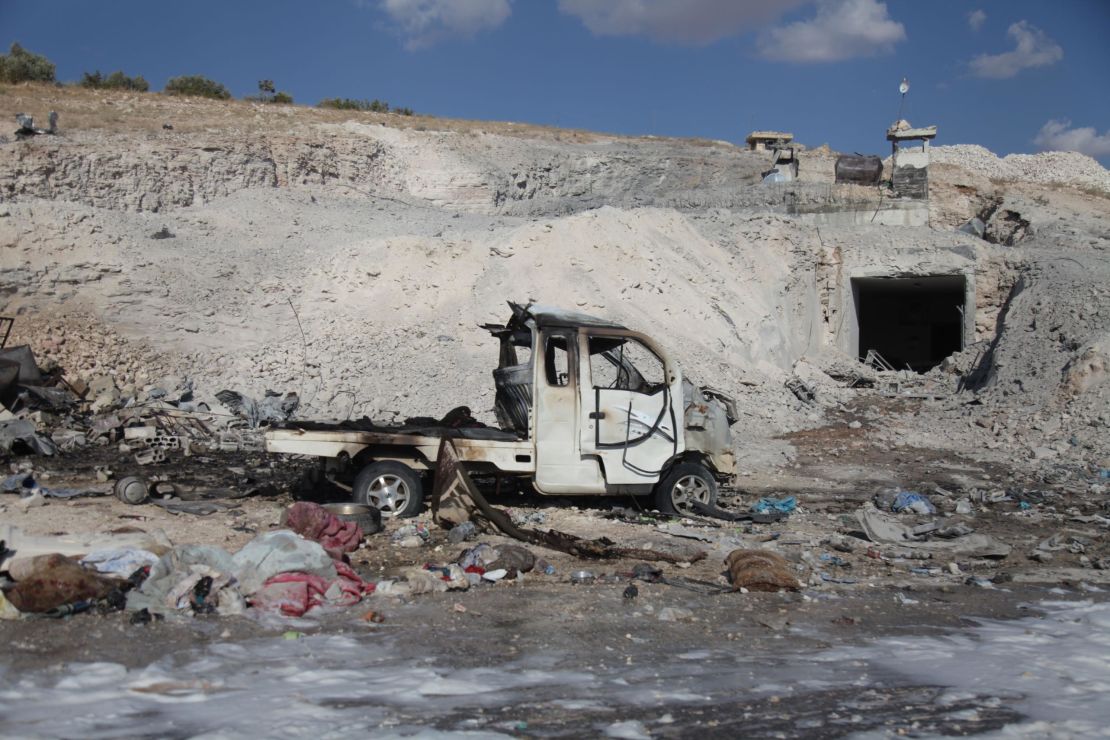 A burned vehicle and personal belongings are seen Saturday in Hass, Syria, after an airstrike.