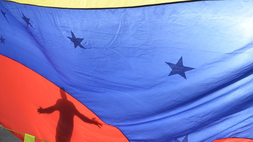 A person's shadow is cast on a Venezuelan national flag in Caracas on July 10, 2017.
Venezuela hit its 100th day of anti-government protests Sunday, amid uncertainty over whether the release from prison a day earlier of prominent political prisoner Leopoldo Lopez might open the way to negotiations to defuse the profound crisis gripping the country. / AFP PHOTO / FEDERICO PARRA        (Photo credit should read FEDERICO PARRA/AFP/Getty Images)