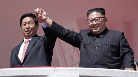 North Korean leader Kim Jong Un, right, raises hands with Chinese envoy Li Zhanshu.