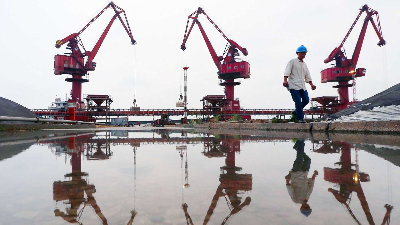 Workers walk as crane buckets transfer soybeans imported from Brazil at a port in Nantong in China's eastern Jiangsu province.