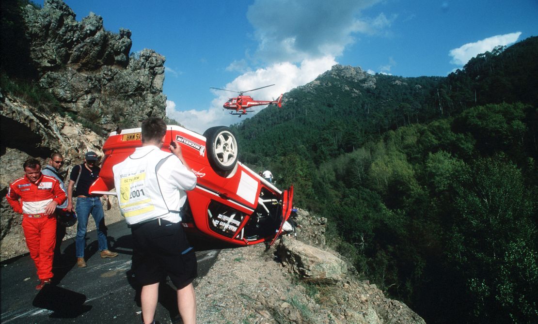 Mäkinen (left) inspects his car after a crash during Rally Corsica in 2001.