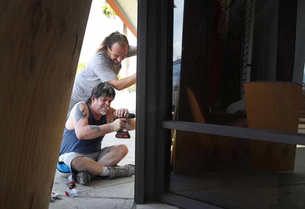 Scott Fleenor, bottom, and Jeremiah Trendell board over the windows of a business in Myrtle Beach.