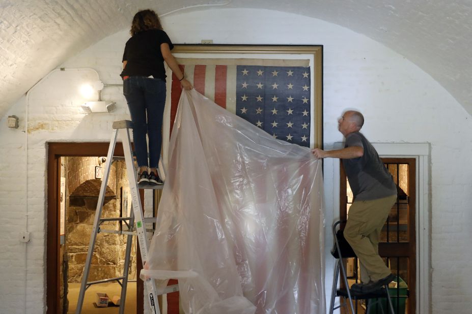 Veronica Gallardo and Robert Kelly place a plastic tarp over an American flag inside the Casemate Museum at Fort Monroe in Hampton, Virginia, on September 11.