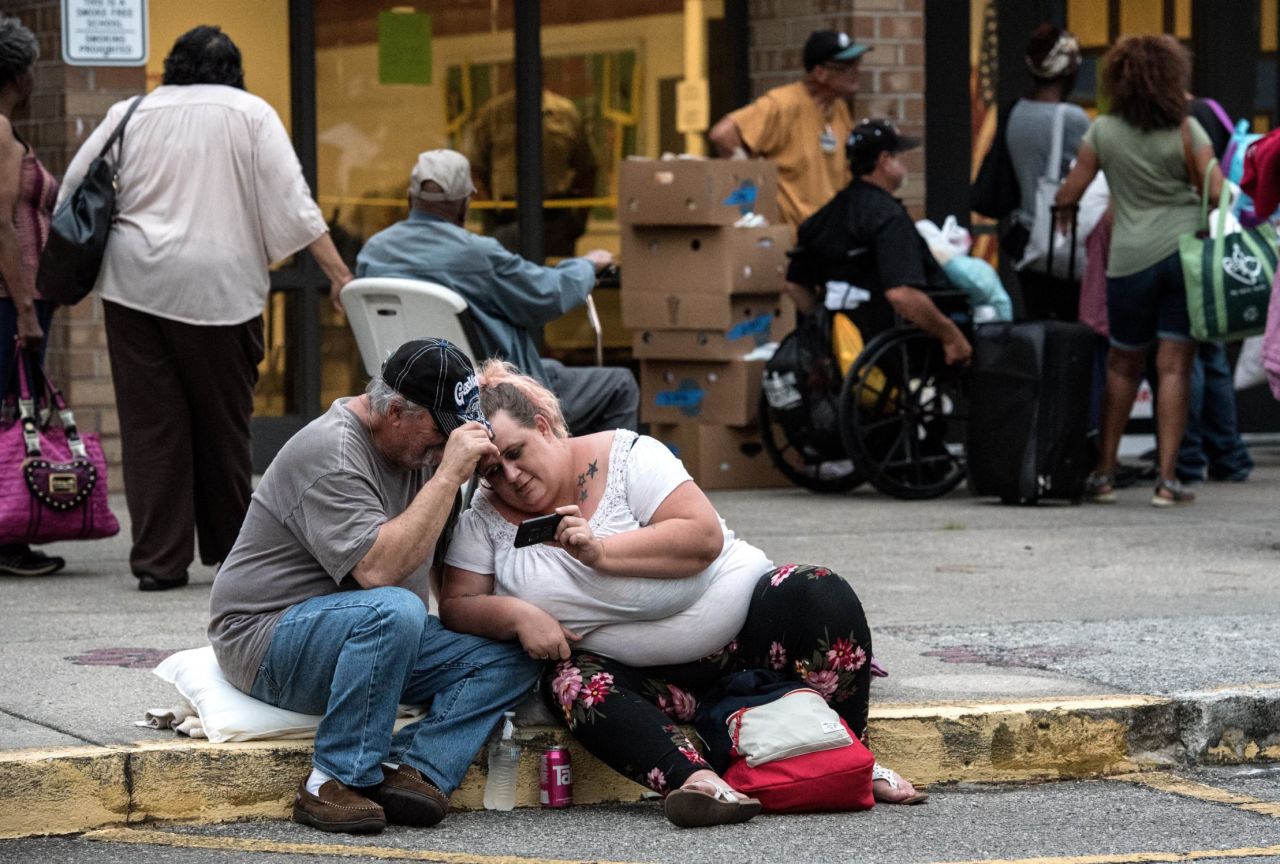 Chuck Ledford, left, watches cartoons on a phone with his daughter Misty as they seek shelter at Emma B. Trask Middle School in Wilmington, North Carolina, on Tuesday, September 11. 