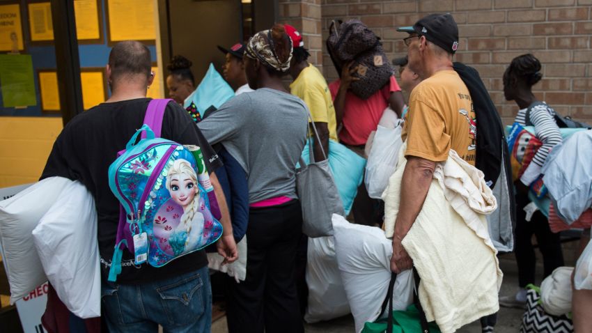 People line up to enter a hurricane shelter at Trask Middle School in wilmington, North Carolina, on September 11, 2018. - Hurricane Florence would deliver a "direct hit" to the US East Coast, emergency officials warned on September 11, 2018. More than one million people in North Carolina, South Carolina and Virginia have been told to flee their homes as the hurricane churns across the Atlantic Ocean towards the coast. (Photo by Andrew CABALLERO-REYNOLDS / AFP)        (Photo credit should read ANDREW CABALLERO-REYNOLDS/AFP/Getty Images)
