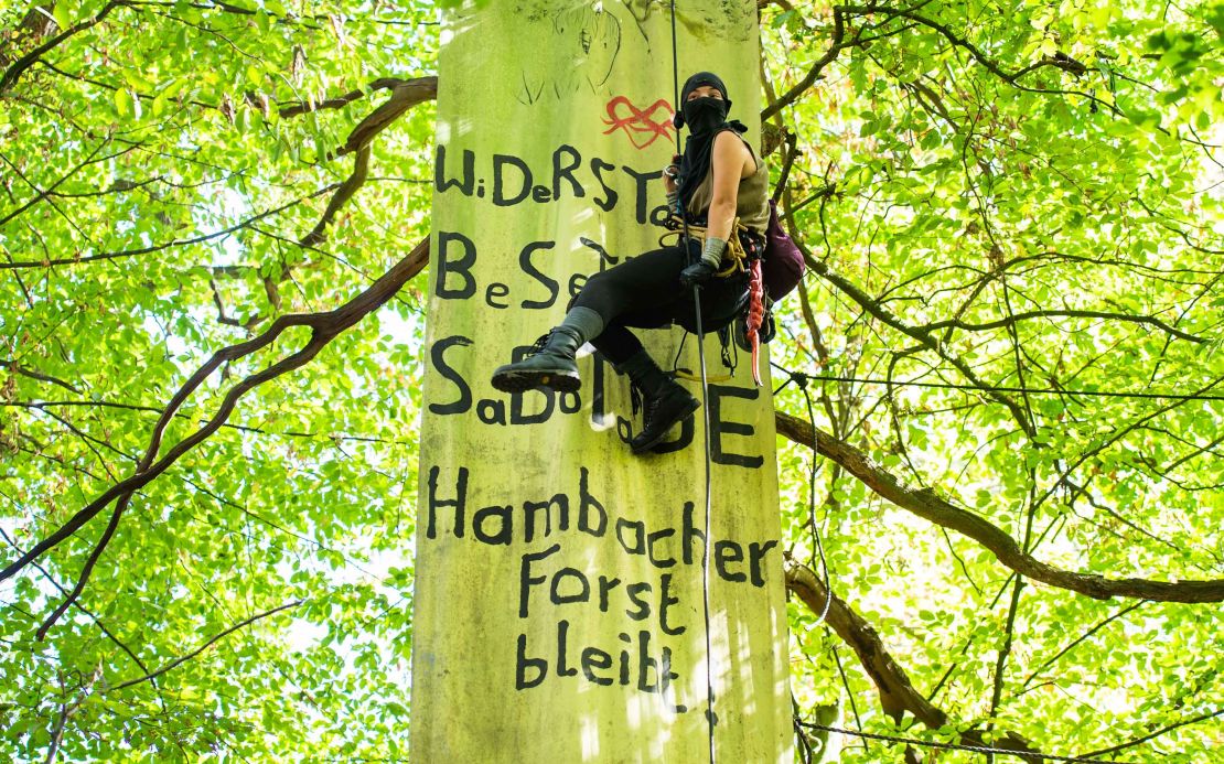 An environmental activist hangs on a rope in the Hambach Forest last month, in front of a banner with the inscription "Resistance, occupation, sabotage, Hambach Forest remains."
