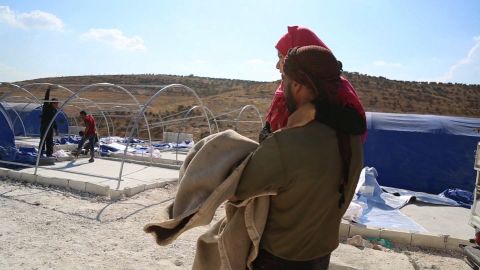 Layla's uncle carries her to her family's newly pitched tent -- she has been unable to walk since birth.