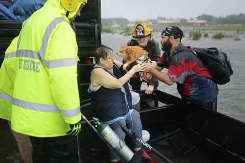 Rescue workers help a woman and her dog from a flooded house in James City on September 14.