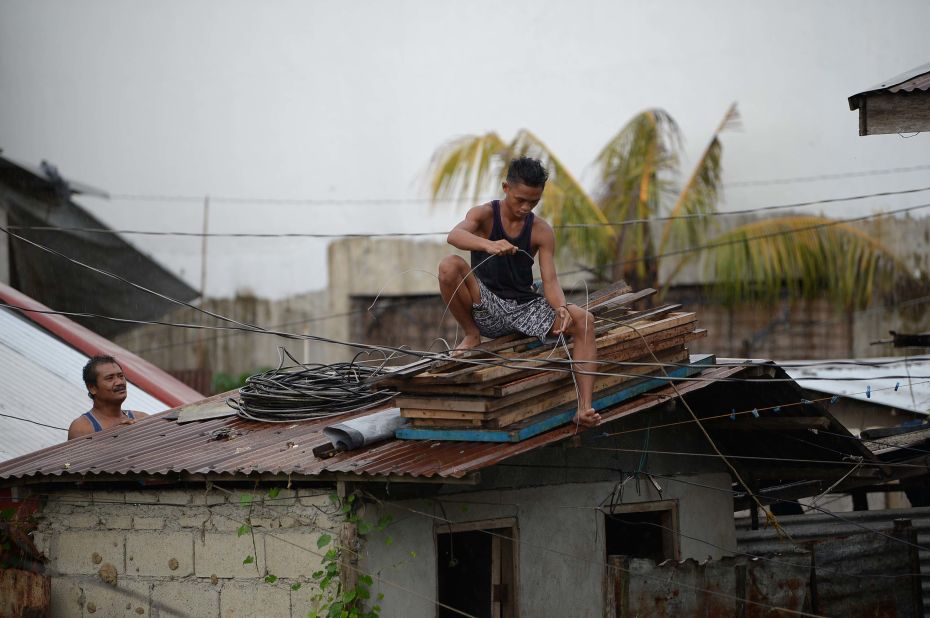 People secure the roof of a house in Tuguegarao on September 14.