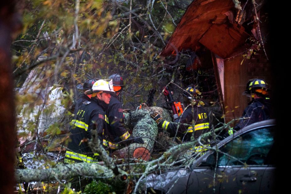 Rescue workers attempt to remove a giant tree that fell onto a house in Wilmington, North Carolina, on September 14. Two people died when the tree collapsed -- among the first storm-related deaths due to Hurricane Florence. 