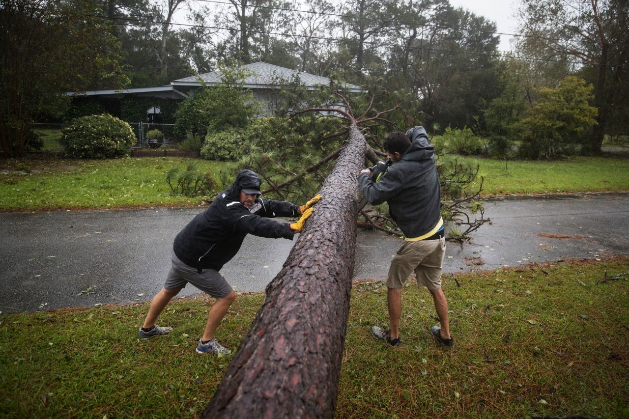 Lee Casteen, left, and Try Hinton use a chainsaw to clear a tree blocking a road in Wilmington on September 14.
