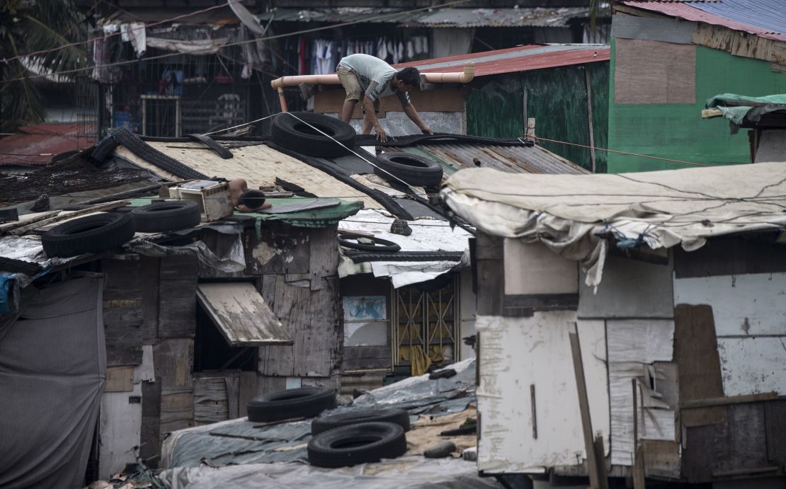 Residents reinforce the roof of their house by putting heavy tires at a slum area in Manila.