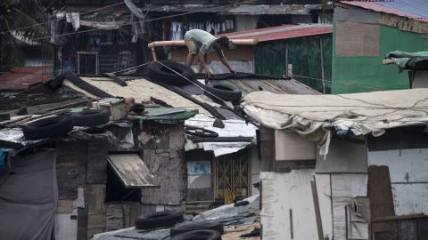 Residents reinforce the roof of their house by putting heavy tires at a slum area in Manila.