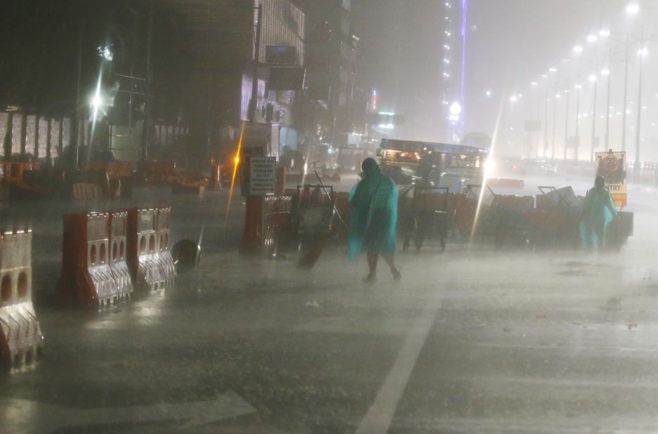 Street sweepers go about their daily business as rain and strong winds pound Manila on September 15.