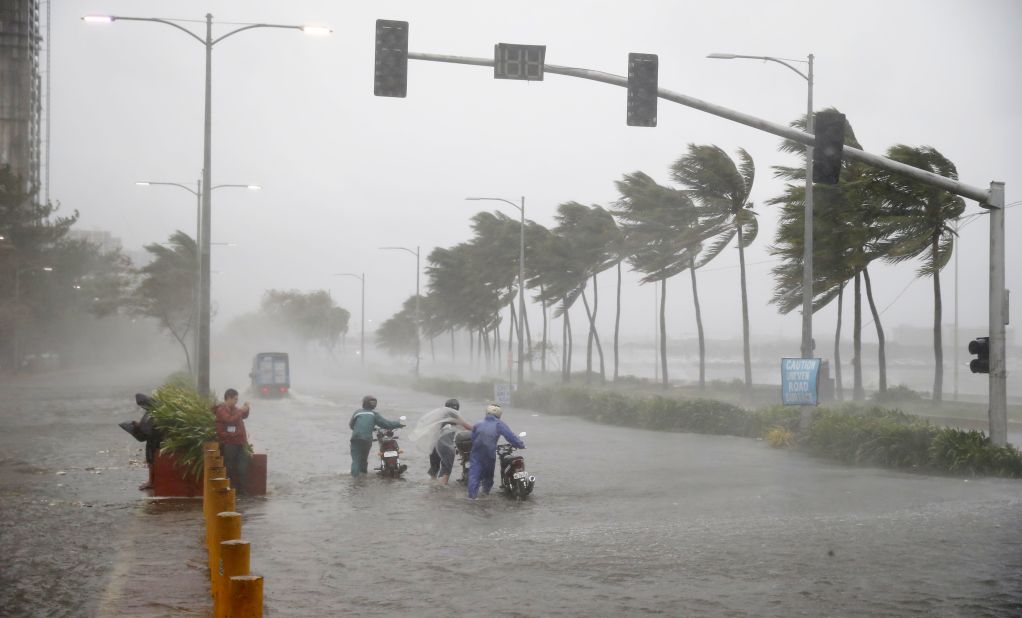 Motorists push their motor bikes through a flooded street in Manila on September 15.