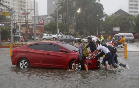 Commuters push a car through floodwaters in Manila on September 15.  