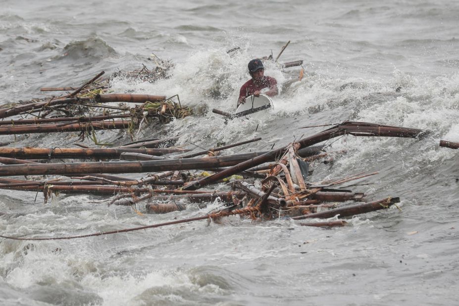 A wave overwhelms a man as he tries to recover salvageable materials in Manila, Philippines, on Saturday, September 15.