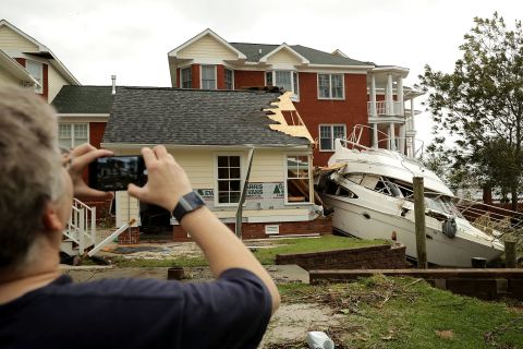 A neighbor takes photos of a boat smashed against a car garage near the Neuse River in New Bern on Saturday.
