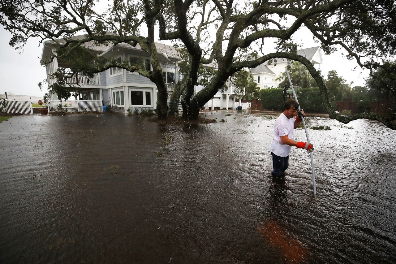 Mike Pollack searches for a drain in the yard of his flooded waterfront home in Wilmington, North Carolina, on Saturday.