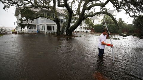 Mike Pollack searches for a drain in the yard of his flooded home in Wilmington, North Carolina.