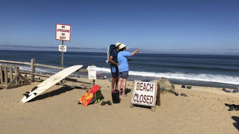 Two people look out at the shore after a reported shark attack at Newcomb Hollow Beach in Wellfleet, Mass, on Saturday, Sept. 15, 2018. A man boogie boarding off the Cape Cod beach was attacked by a shark on Saturday and died later at a hospital, becoming the state's first shark attack fatality in more than 80 years. (AP Photo/Susan Haigh)